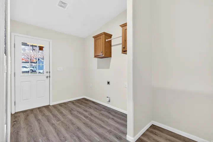 Laundry area featuring hookup for an electric dryer, wood finished floors, and cabinet space
