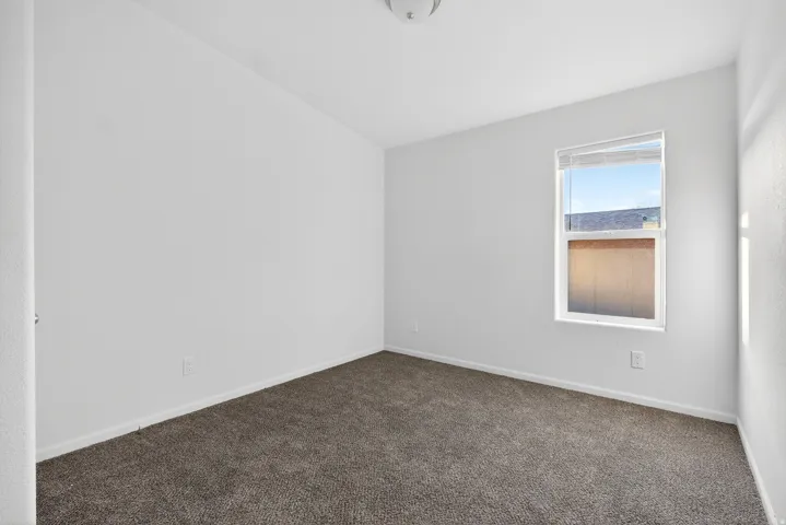 Spare room featuring dark carpet and baseboards