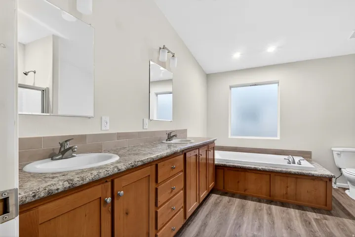 Full bath with a garden tub, double vanity, and light wood-style flooring