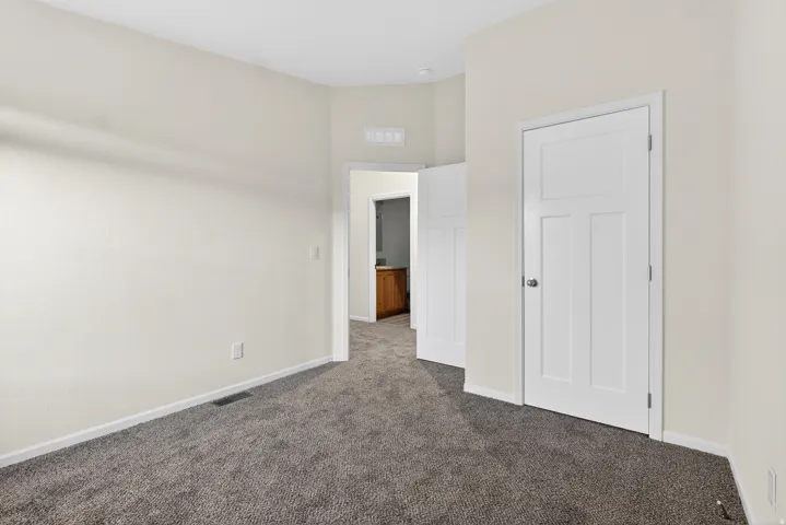 Unfurnished bedroom with dark carpet and baseboards
