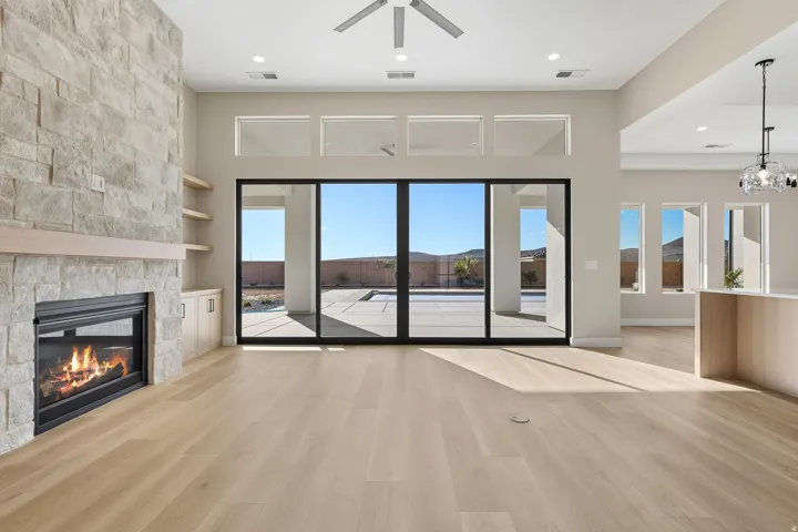 Unfurnished living room featuring light wood-type flooring, healthy amount of natural light, built in features, recessed lighting, and a stone fireplace