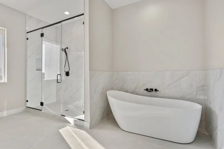 Bathroom with a marble finish shower, a freestanding tub, tile walls, tile patterned flooring, and wainscoting