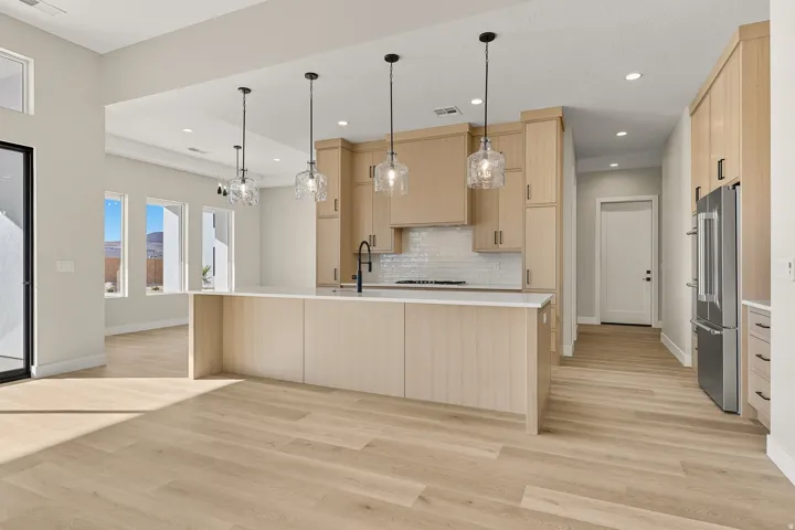 Kitchen featuring light brown cabinets, high end fridge, decorative light fixtures, light wood finished floors, and recessed lighting