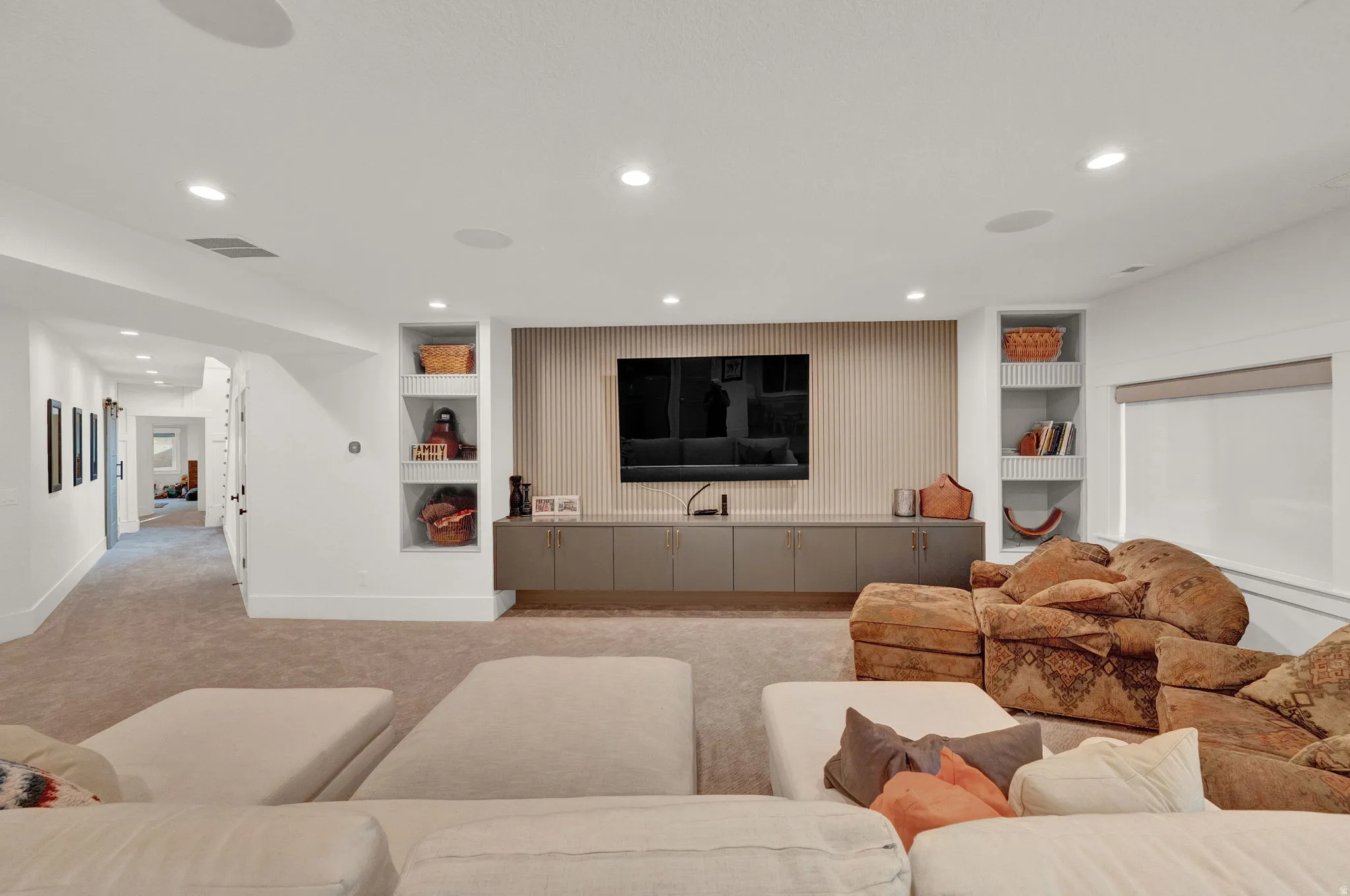 Living area with built in features, light colored carpet, and recessed lighting