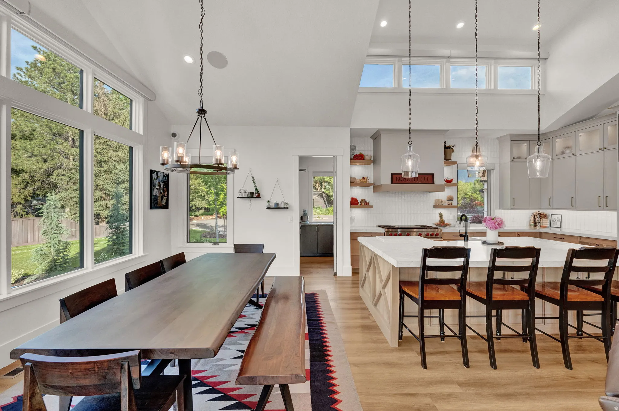 Dining area featuring high vaulted ceiling, healthy amount of natural light, light wood finished floors, recessed lighting, and a chandelier