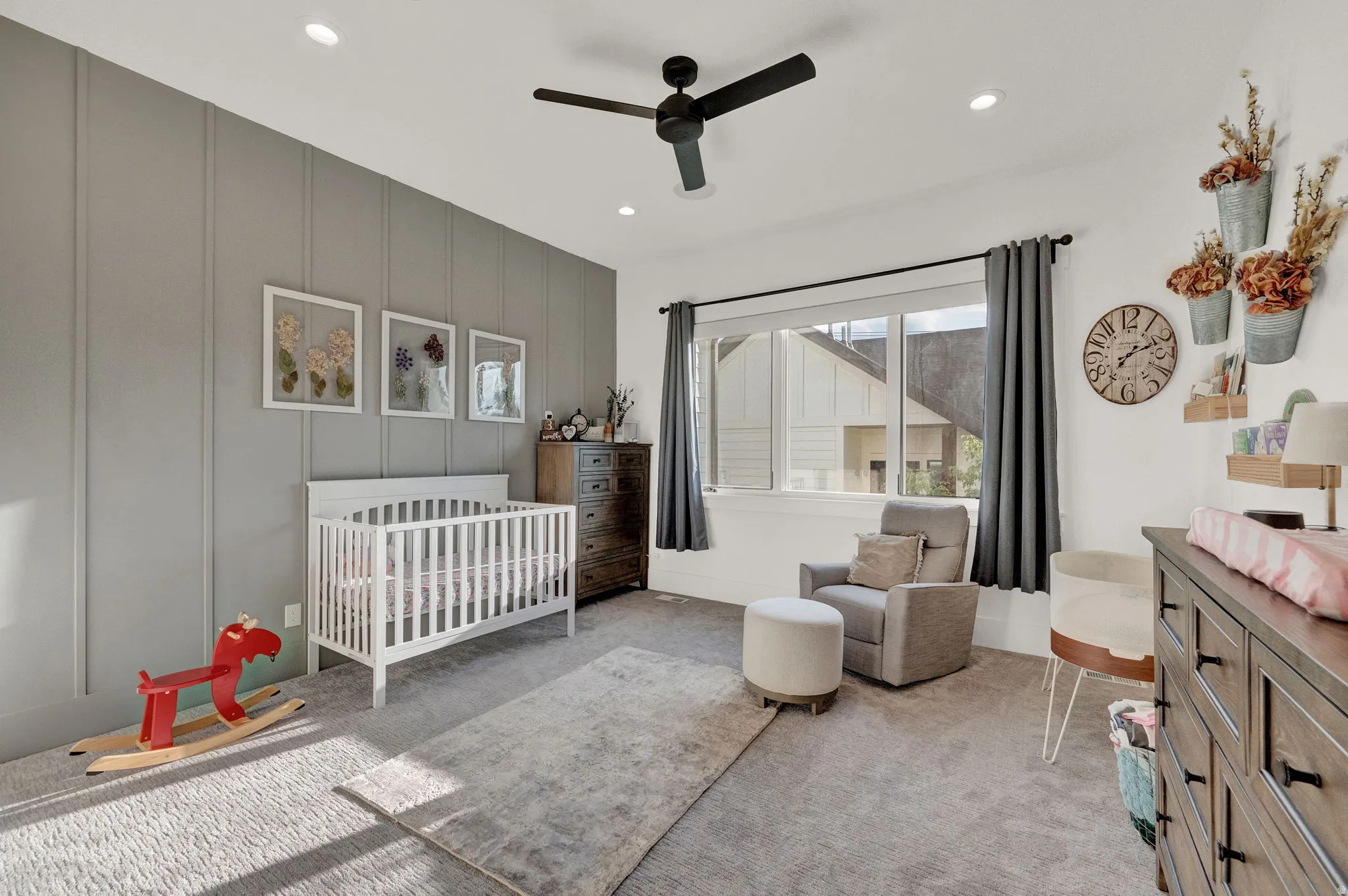 Bedroom with a decorative wall, a nursery area, light colored carpet, ceiling fan, and an accent wall