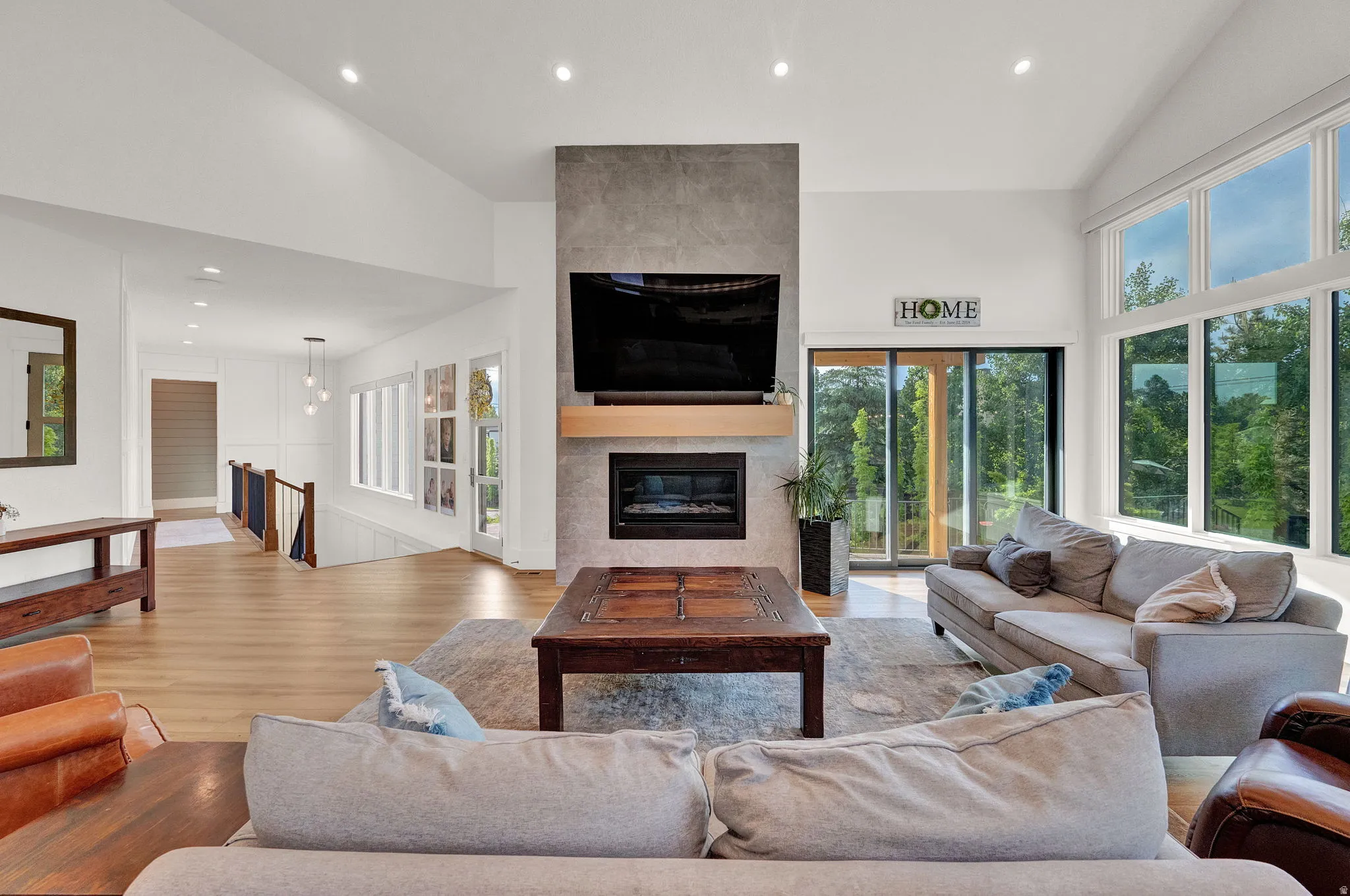 Living room with high vaulted ceiling, recessed lighting, a fireplace, and light wood-type flooring