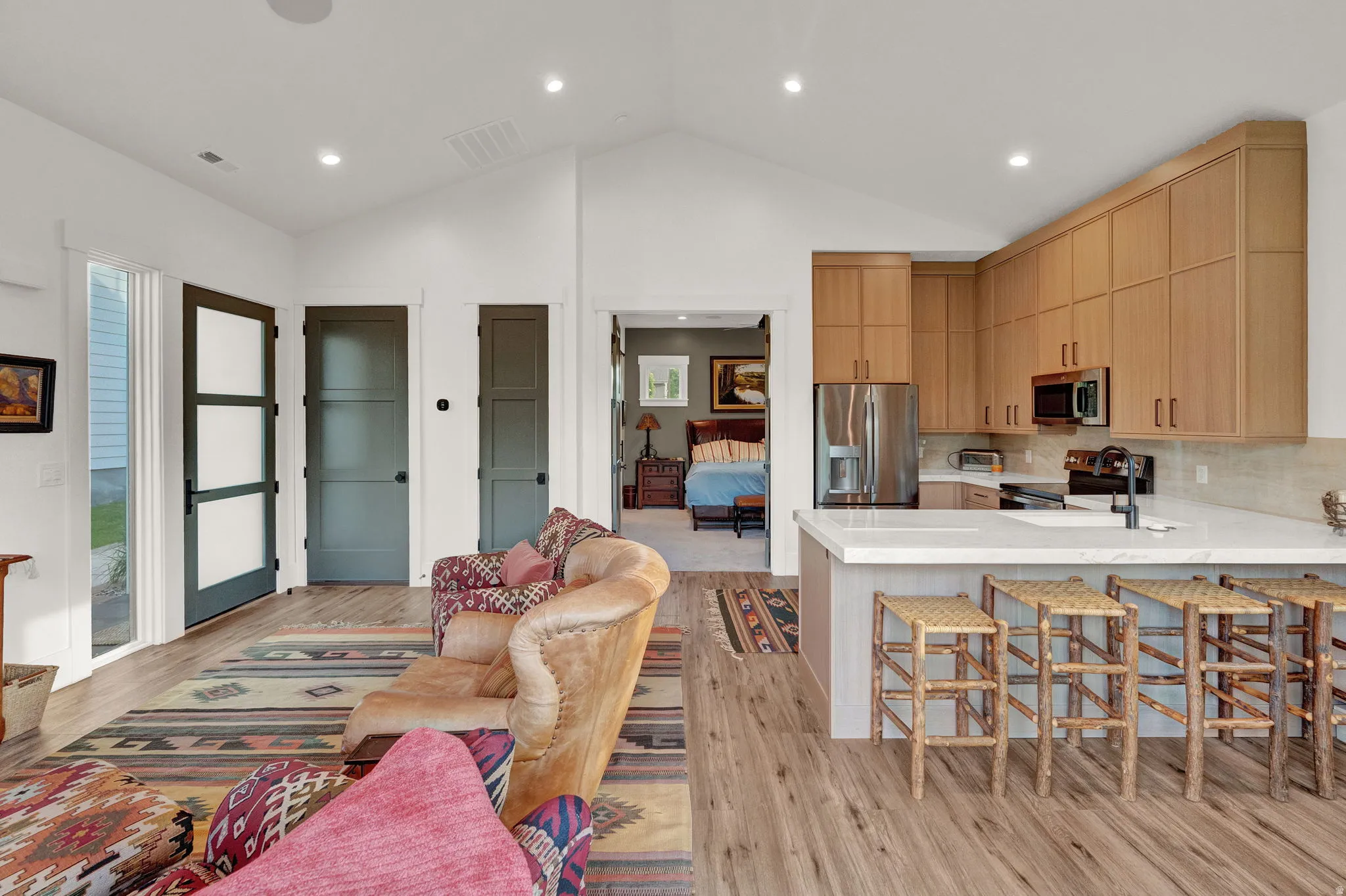 Kitchen with a peninsula, a breakfast bar area, light wood-style flooring, light brown cabinets, and vaulted ceiling