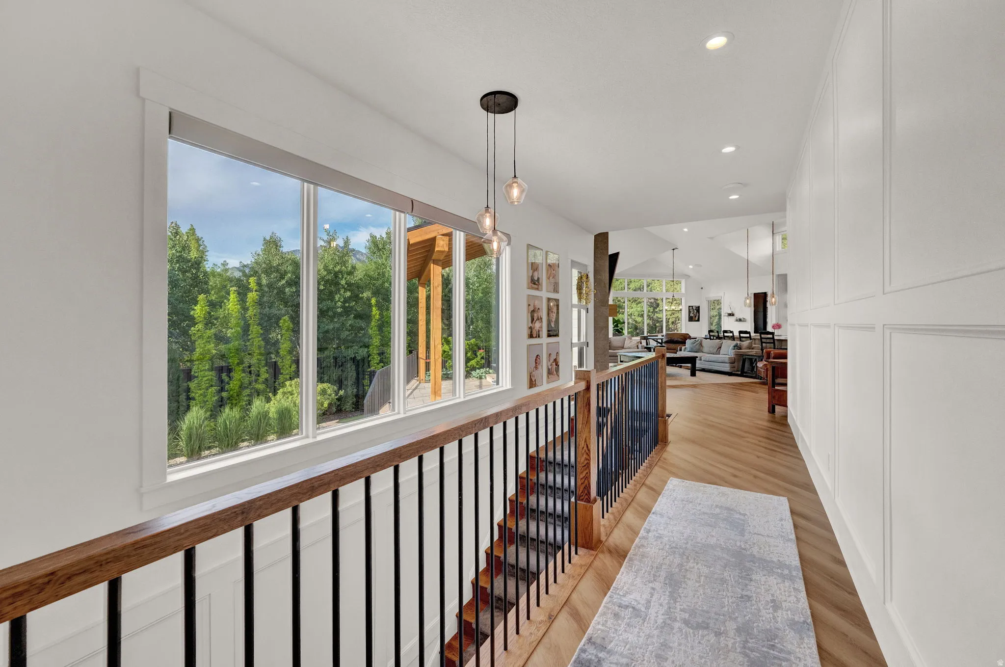 Hall with light wood-style flooring, an upstairs landing, recessed lighting, and a decorative wall