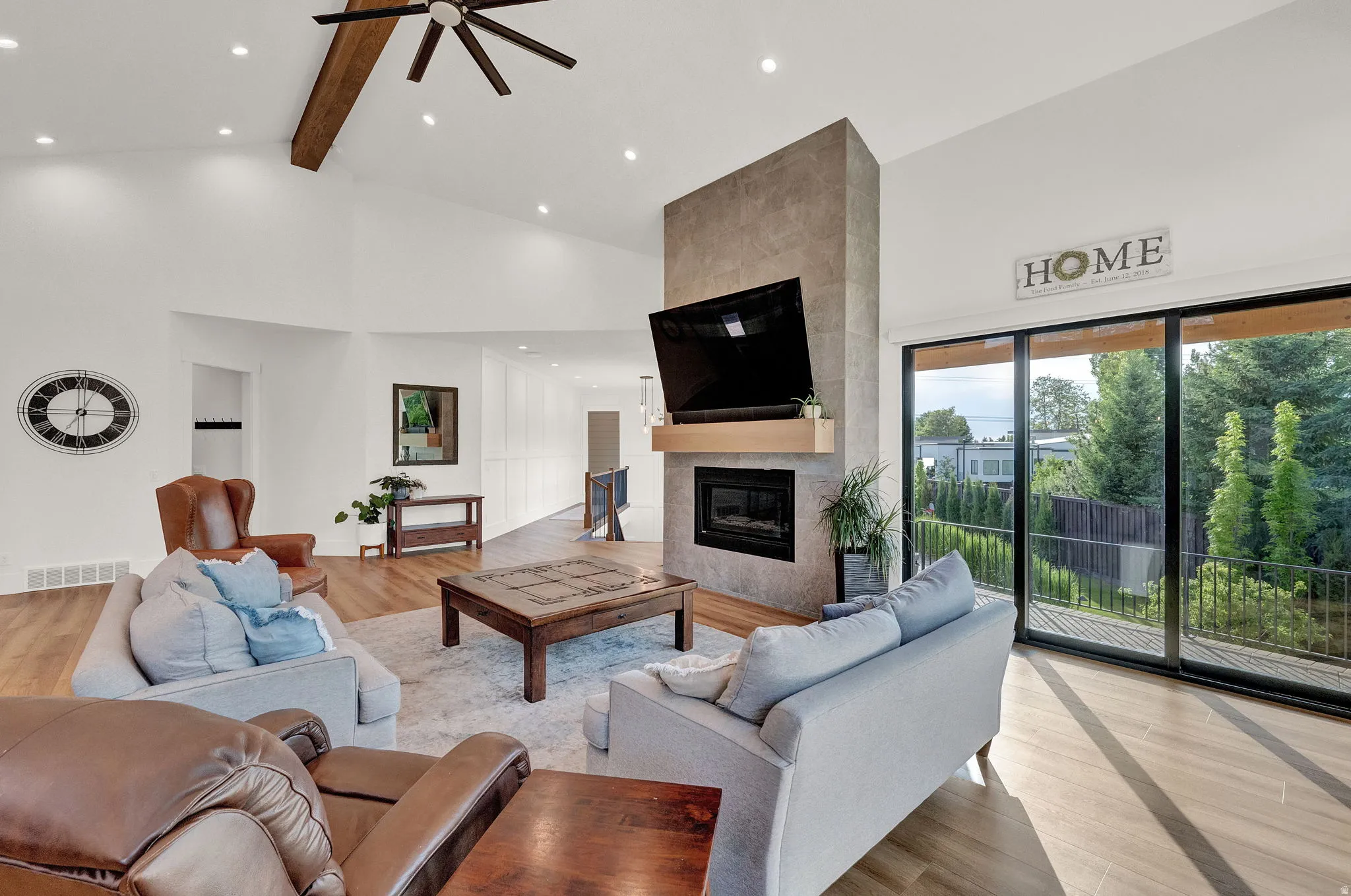 Living room with light wood-style flooring, a fireplace, high vaulted ceiling, recessed lighting, and a ceiling fan