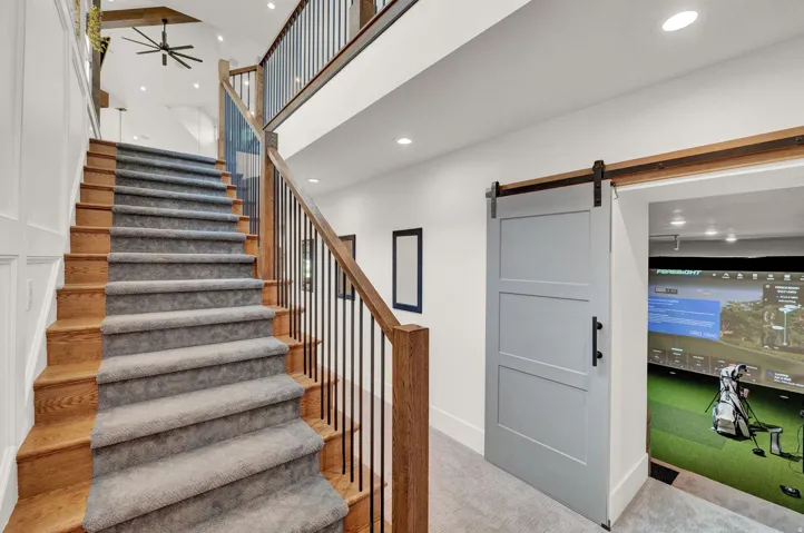 Stairs with a barn door, a high ceiling, carpet flooring, recessed lighting, and golf simulator