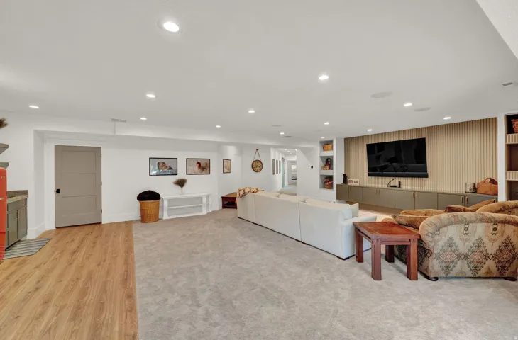 Living room with built in shelves, light wood finished floors, and recessed lighting