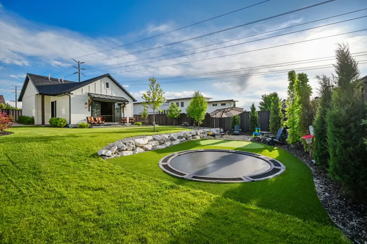 Fenced backyard with a trampoline and a patio area