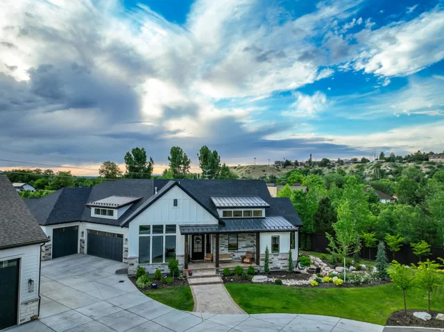 Modern inspired farmhouse featuring stone siding, a standing seam roof, a metal roof, concrete driveway, and board and batten siding