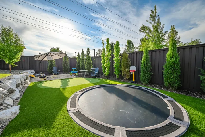Fenced backyard featuring an area to practice putting and a patio area