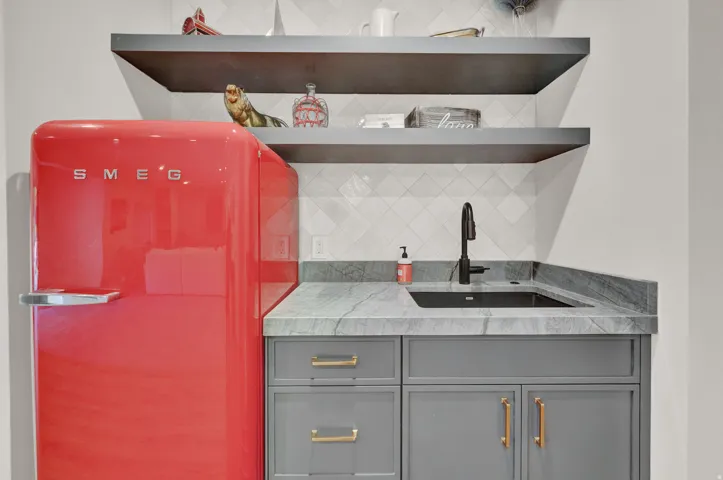 Indoor wet bar with gray cabinetry, tasteful backsplash, freestanding refrigerator, and open shelves