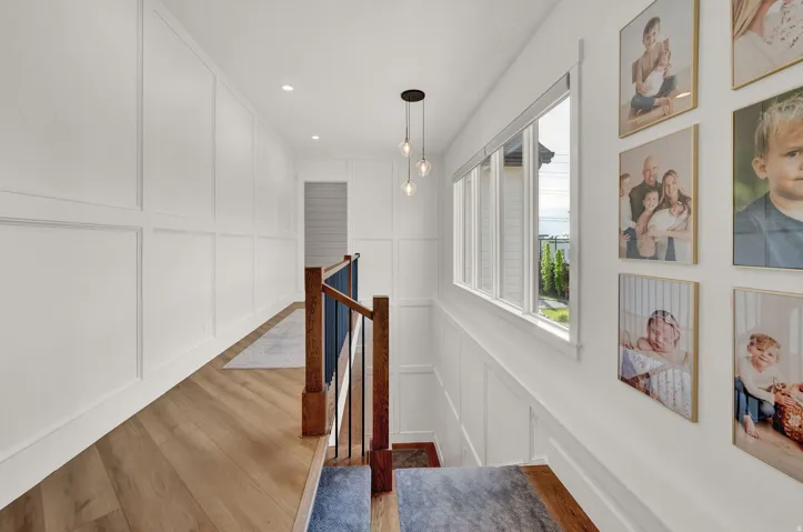 Hall with a decorative wall, an upstairs landing, light wood-type flooring, and recessed lighting