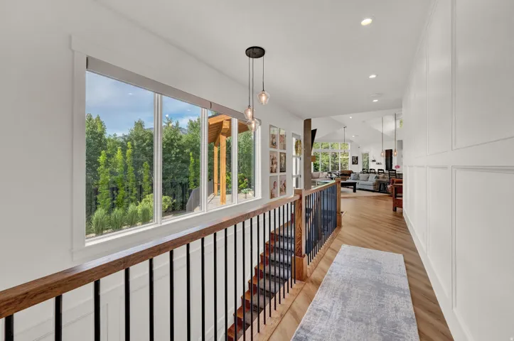 Hall with light wood-style flooring, an upstairs landing, recessed lighting, and a decorative wall