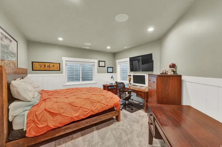 Bedroom with a wainscoted wall, light colored carpet, an office area, and recessed lighting