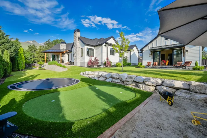 View of grassy yard featuring a putting green and a patio