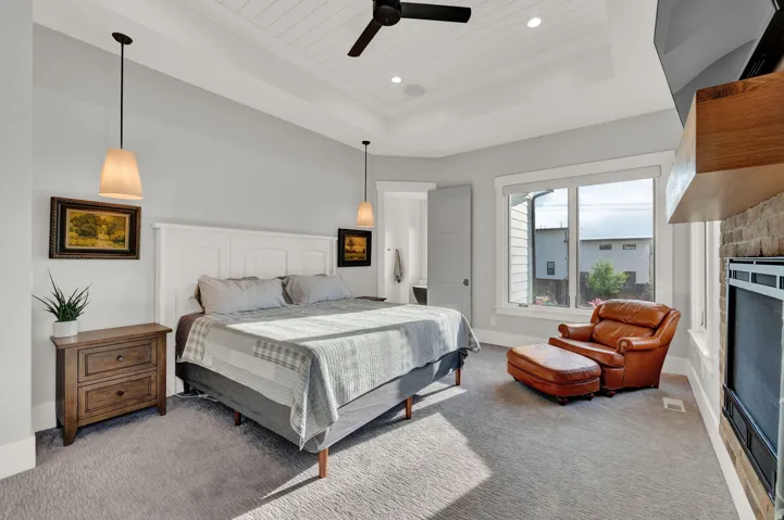 Bedroom featuring a raised ceiling, carpet floors, ceiling fan, a fireplace, and wooden ceiling