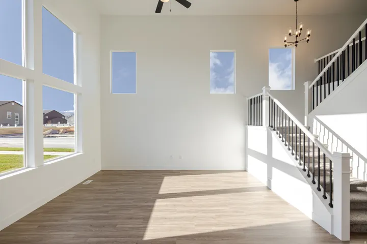 Unfurnished living room featuring dark wood-style flooring, a high ceiling, suspended lighting, and a ceiling fan