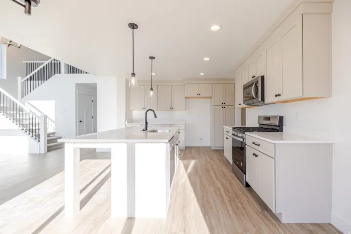 Kitchen with stainless steel appliances, light wood-style flooring, a breakfast bar area, and white cabinetry