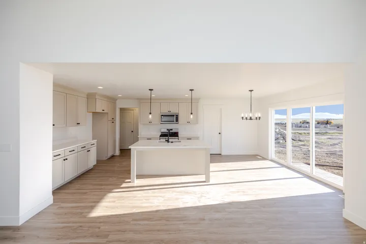 Kitchen featuring light wood-style flooring, a kitchen island with sink, a chandelier, stainless steel appliances, and light stone countertops