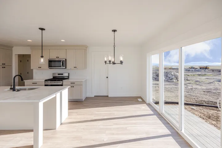 Kitchen featuring stainless steel appliances, light wood-style floors, a chandelier, and light stone countertops