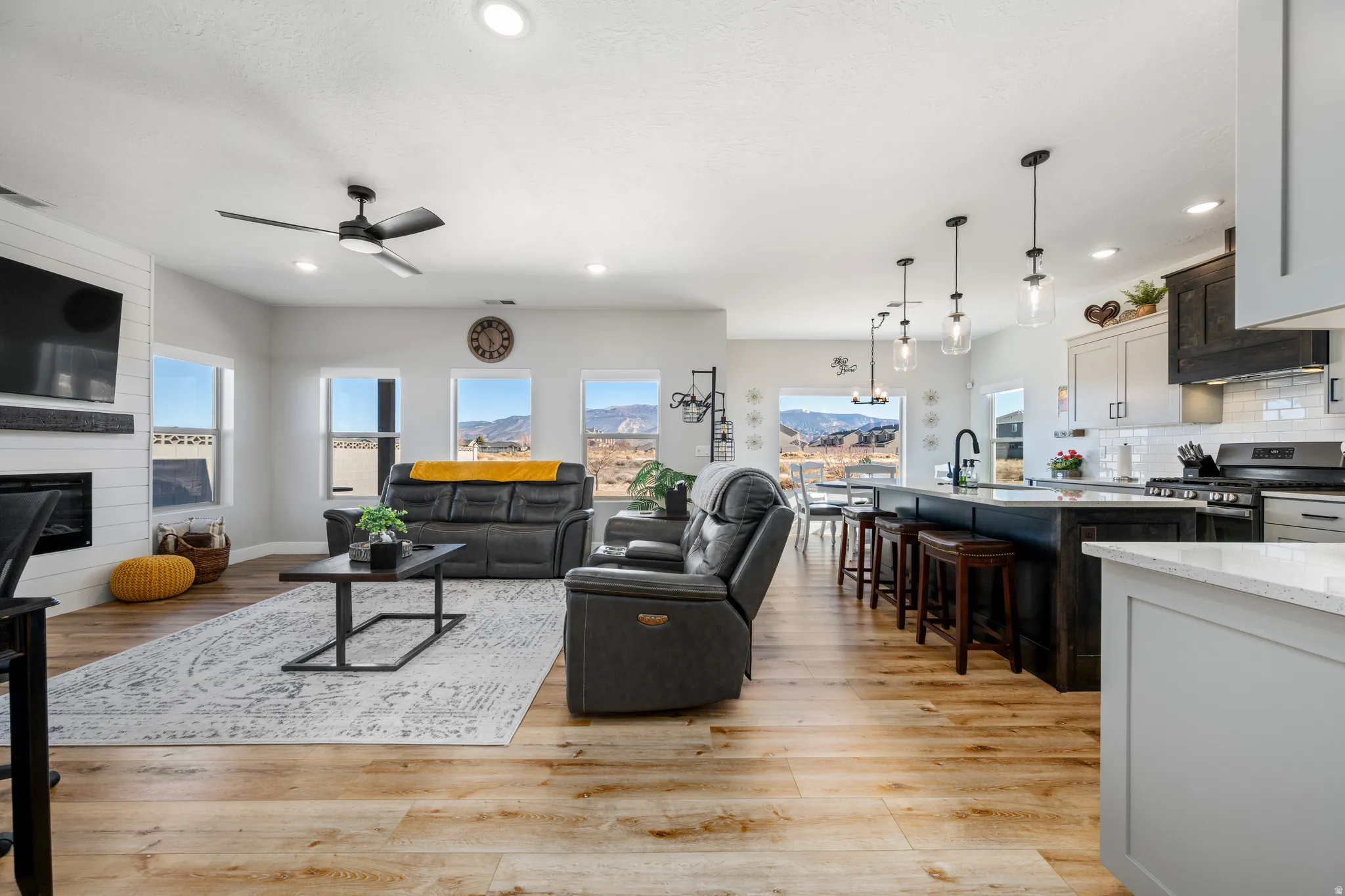 Living area with a large fireplace, light wood-style floors, recessed lighting, and ceiling fan