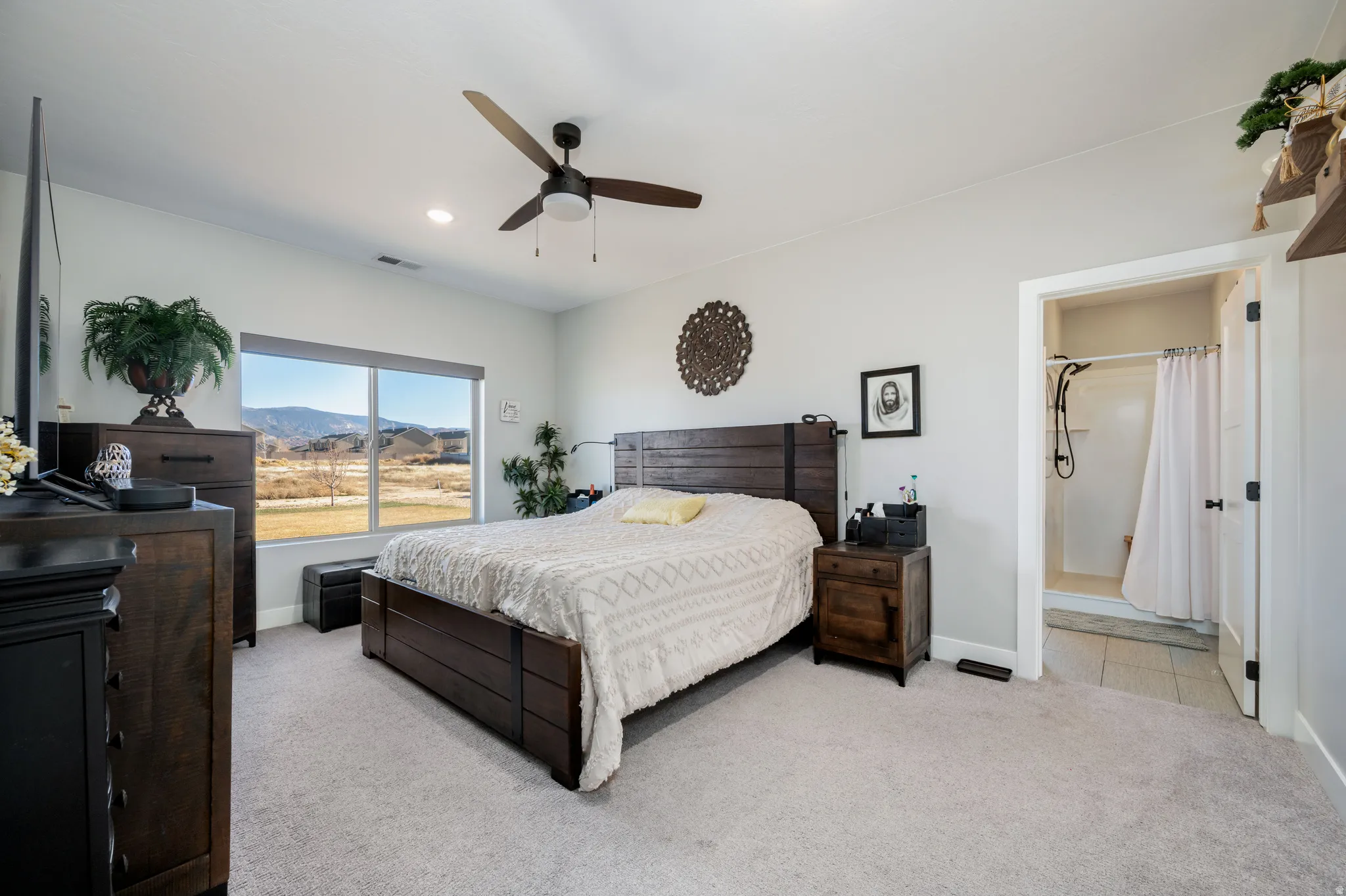 Bedroom with light carpet, ceiling fan, and a mountain view