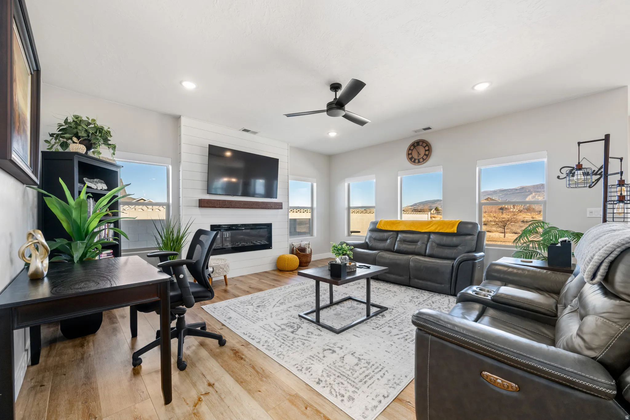 Living room featuring light wood-style flooring, ceiling fan, a fireplace, recessed lighting, and a desk