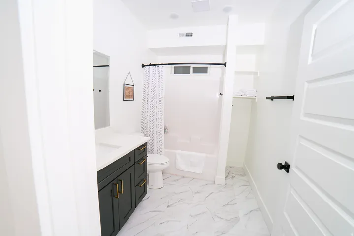 Full bath featuring vanity, shower / bathtub combination with curtain, and light marble finish floors