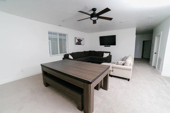 Living area featuring light colored carpet and a ceiling fan