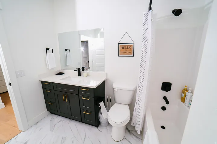 Bathroom featuring light marble finish floors, vanity, and washtub / shower combination