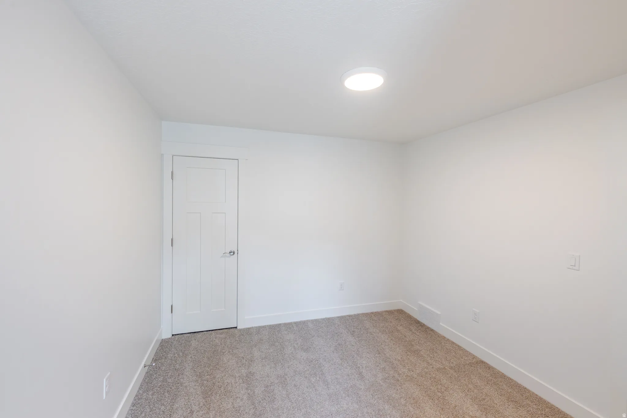 Spare room with baseboards and light colored carpet