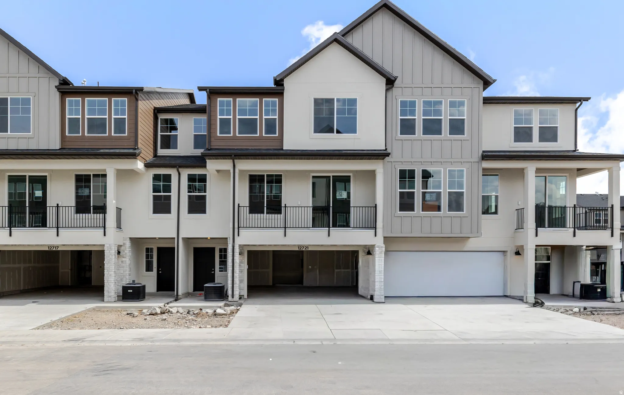 View of front of property with a balcony, board and batten siding, an attached garage, driveway, and stucco siding