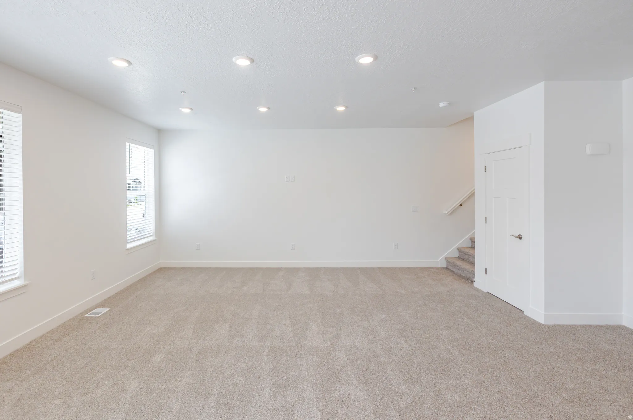 Spare room with light carpet, a textured ceiling, and recessed lighting