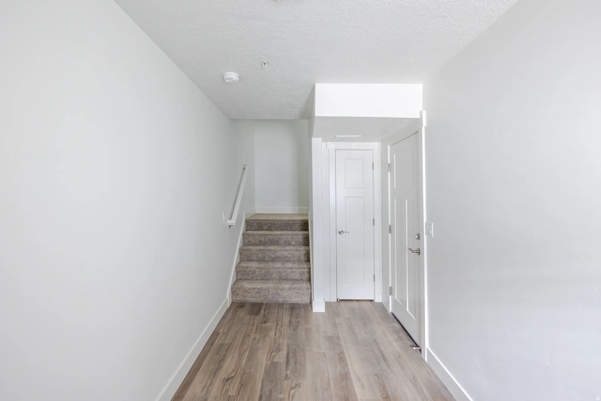 Staircase with wood finished floors and a textured ceiling