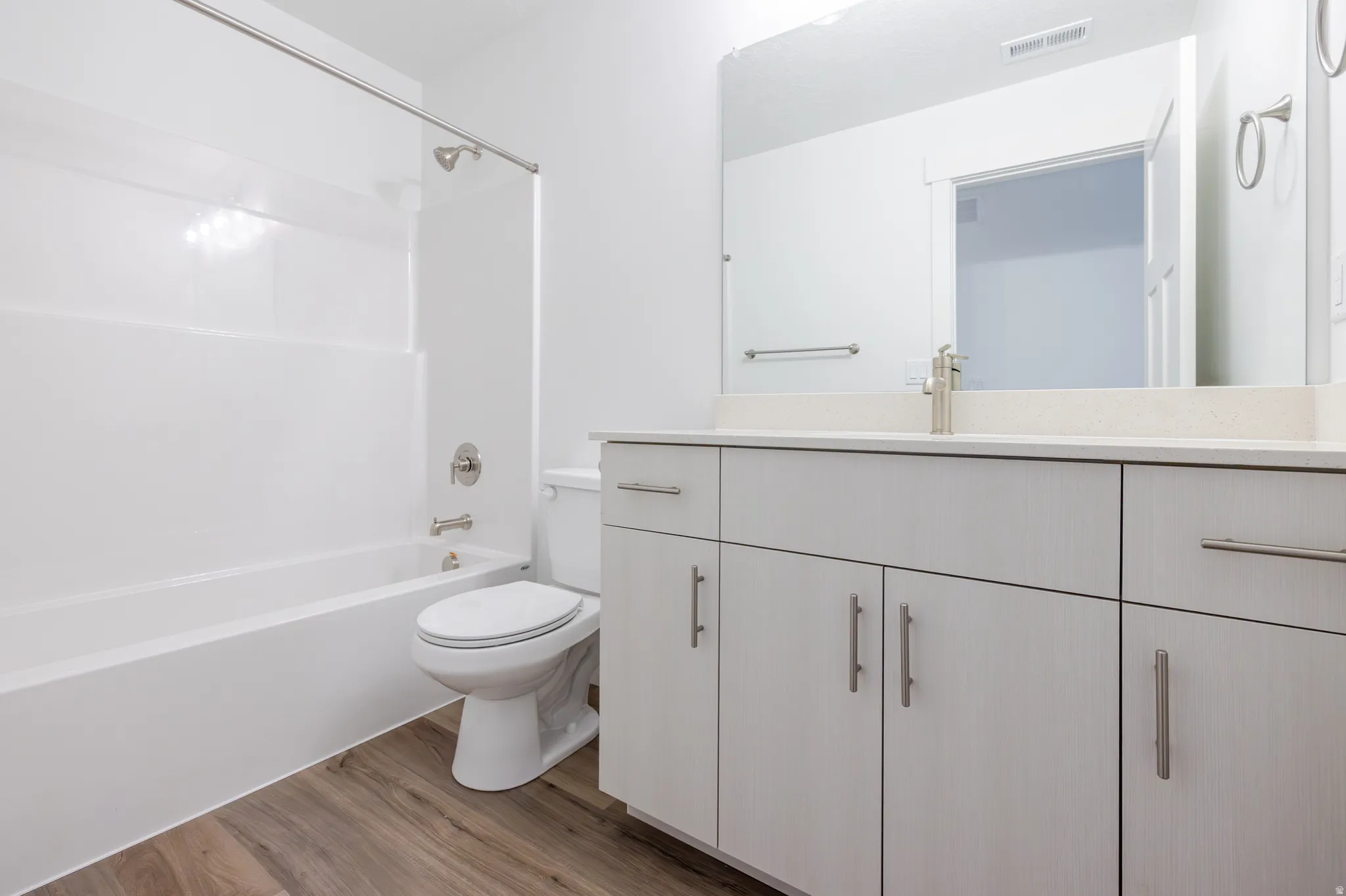 Full bath with vanity, wood finished floors, and shower / tub combination