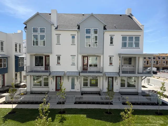 Back of property with a balcony, stucco siding, a shingled roof, and a fenced front yard