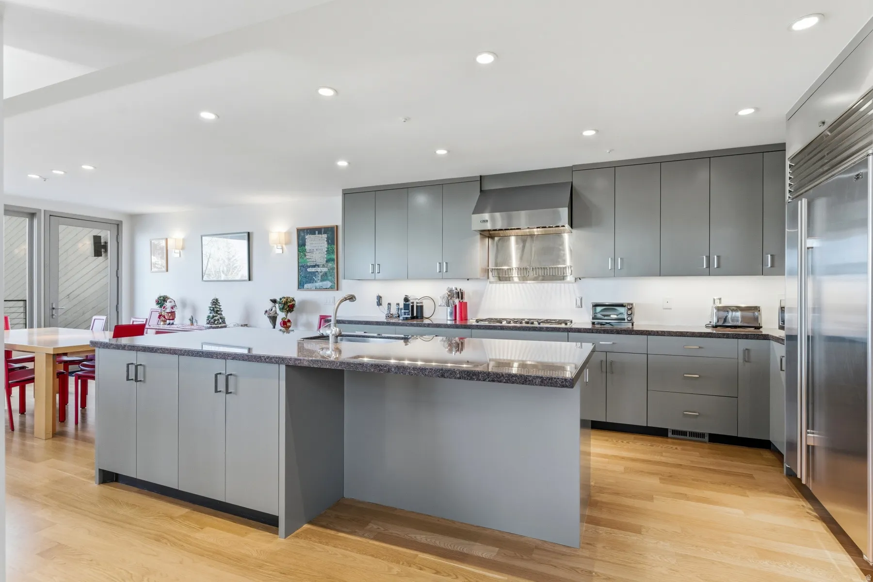 Kitchen with gray cabinets, a kitchen island with sink, recessed lighting, stainless steel appliances, and light wood-type flooring