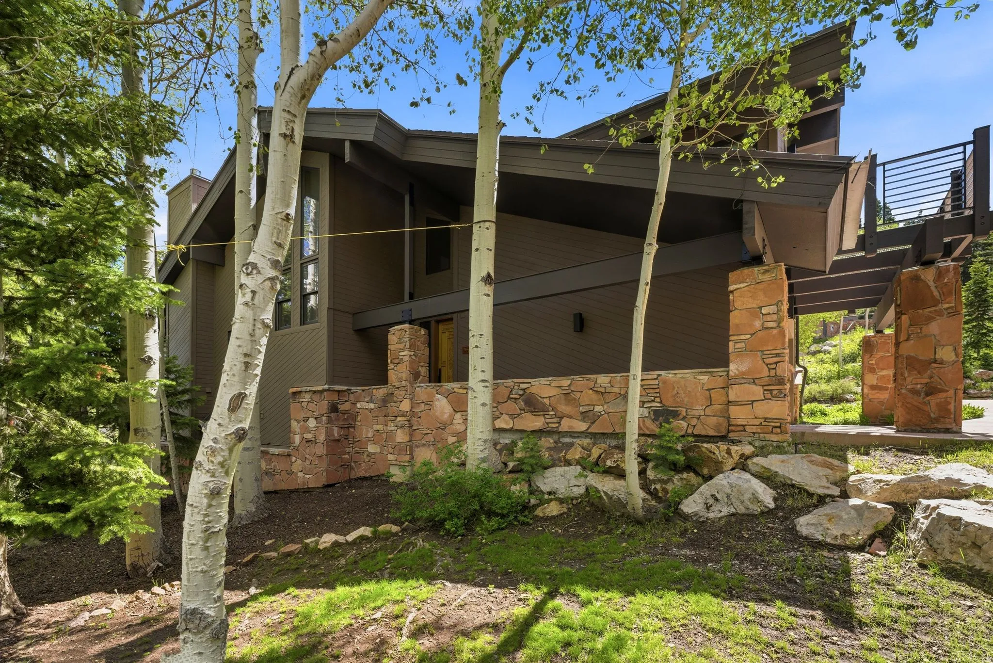 Modern architectural design with a dark brown exterior, stone facade accents, and a distinctive angled roofline