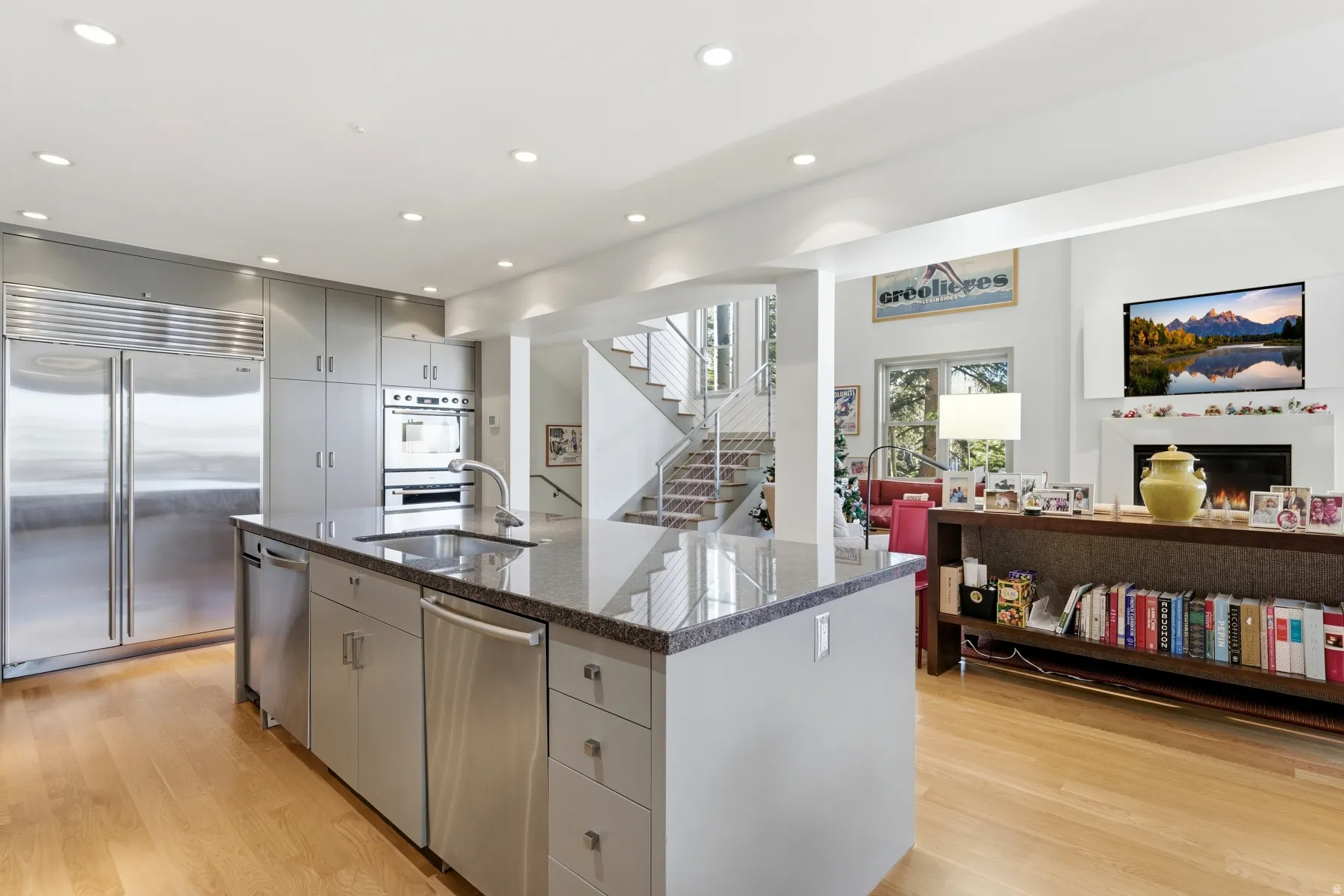 Kitchen featuring appliances with stainless steel finishes, open floor plan, recessed lighting, light wood-type flooring, and an island with sink