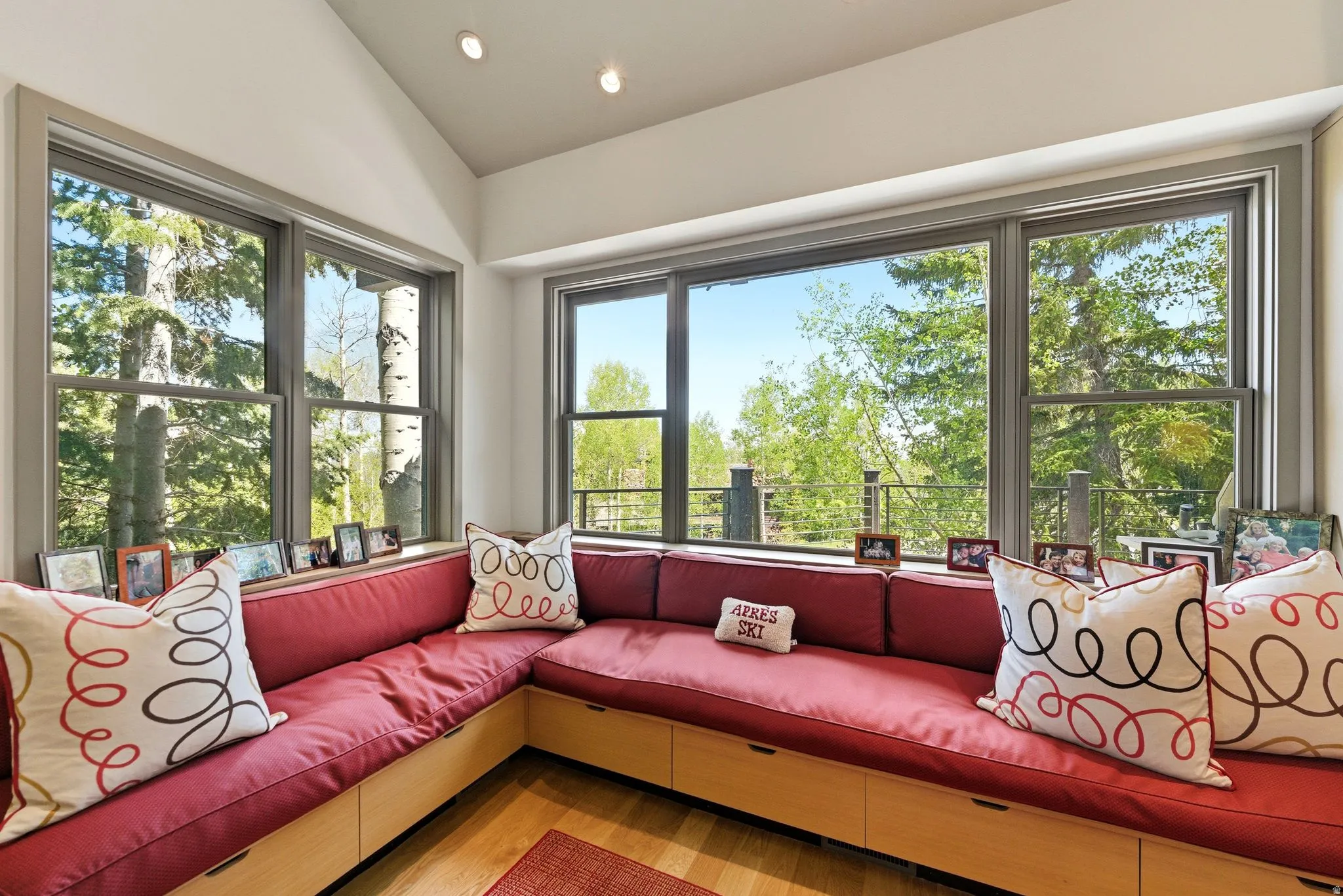 Corner window seating with built-in storage drawers, natural wood-finish flooring, recessed lighting, and a vaulted ceiling
