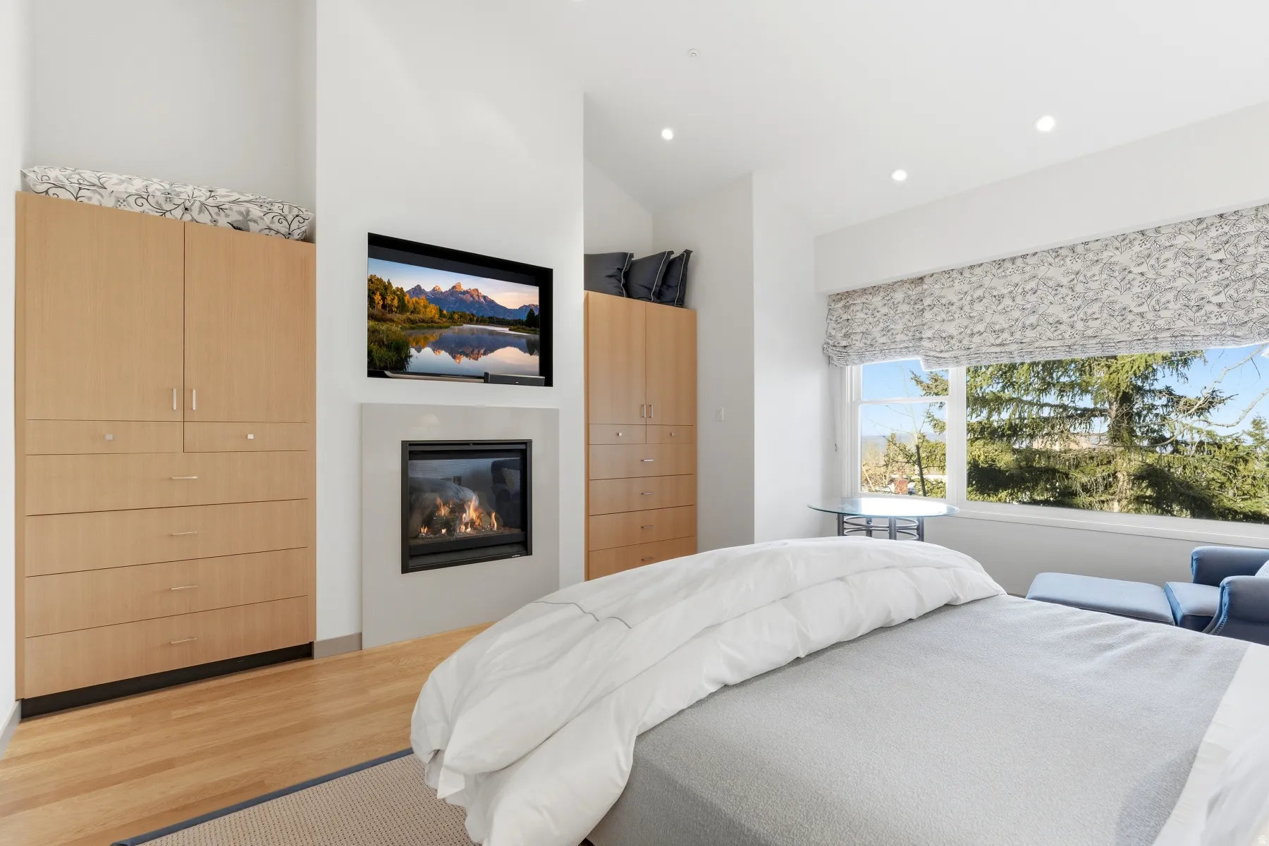 Bedroom featuring a glass covered fireplace, wood finished floors, recessed lighting, and vaulted ceiling