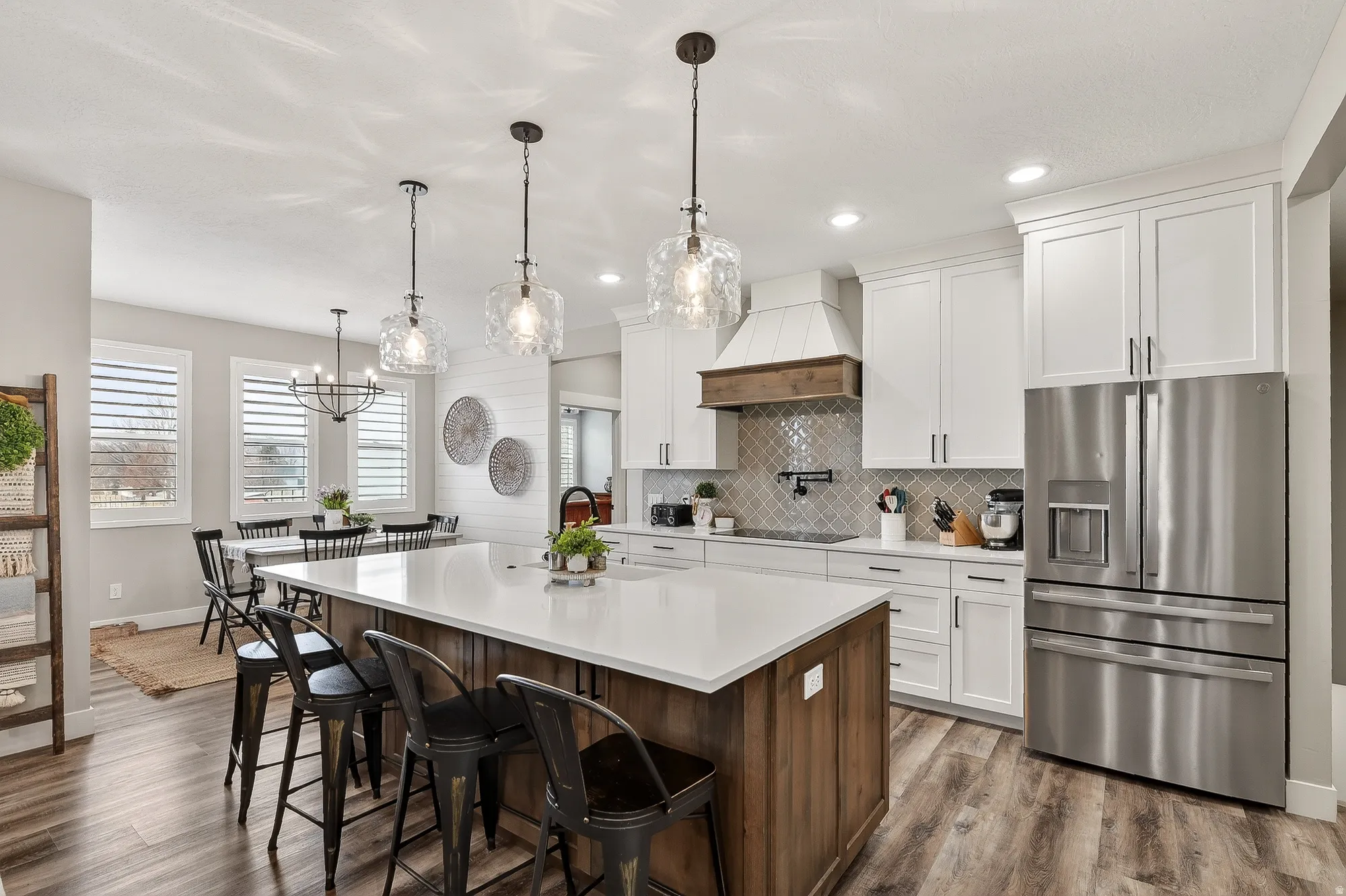 Kitchen featuring stainless steel refrigerator with ice dispenser, two tone cabinets, an island with sink, dark wood-style flooring, and a breakfast bar area