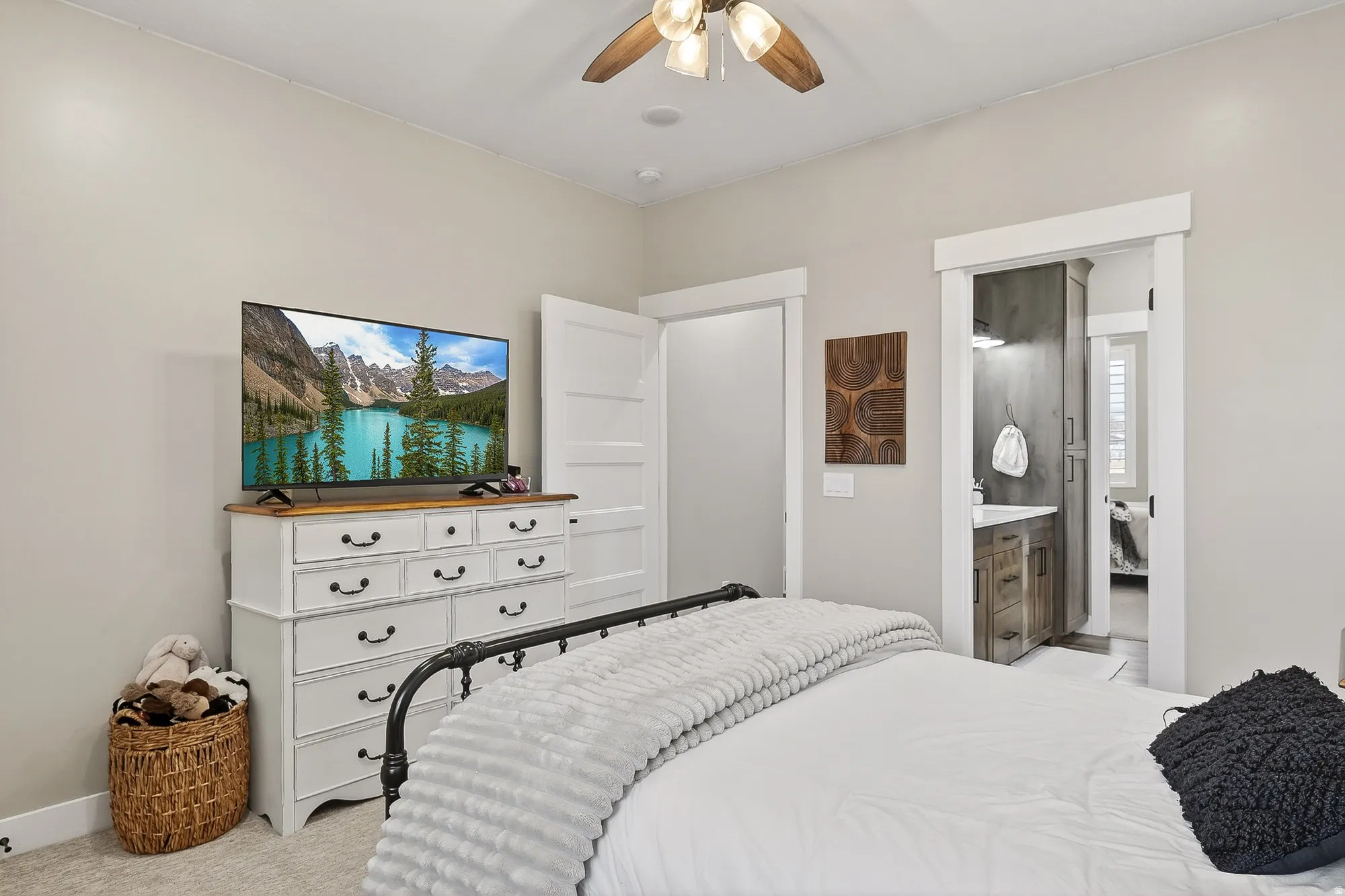 Bedroom featuring light carpet, ceiling fan, and ensuite bath