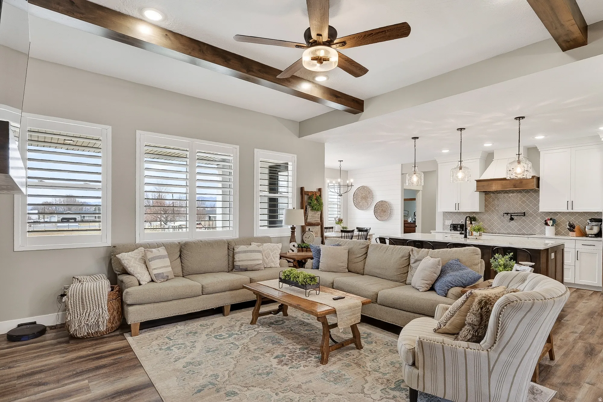 Living area featuring a ceiling fan, dark wood-type flooring, beam ceiling, and a chandelier