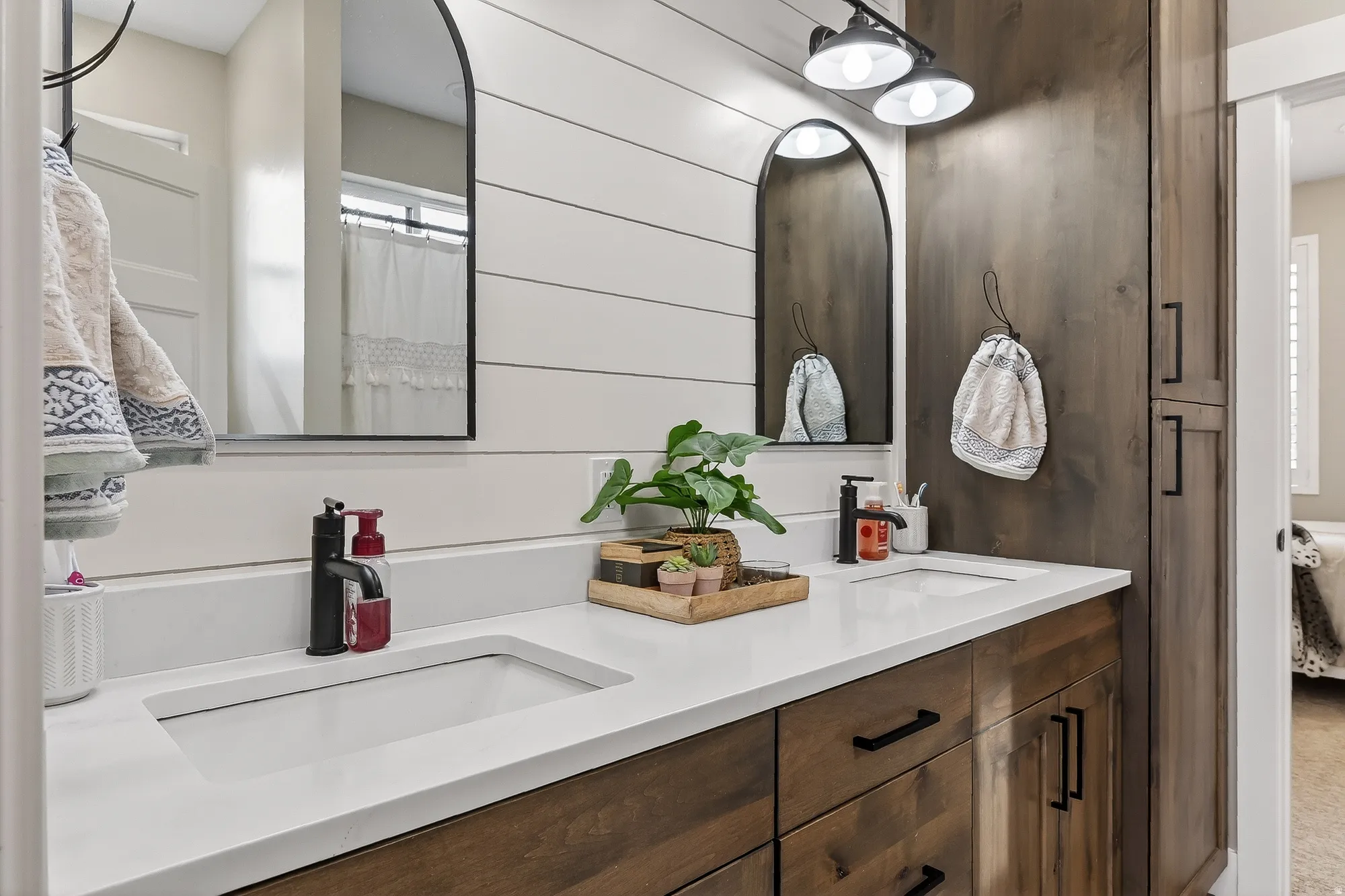 Bathroom with double vanity, a shower with curtain, and wood walls